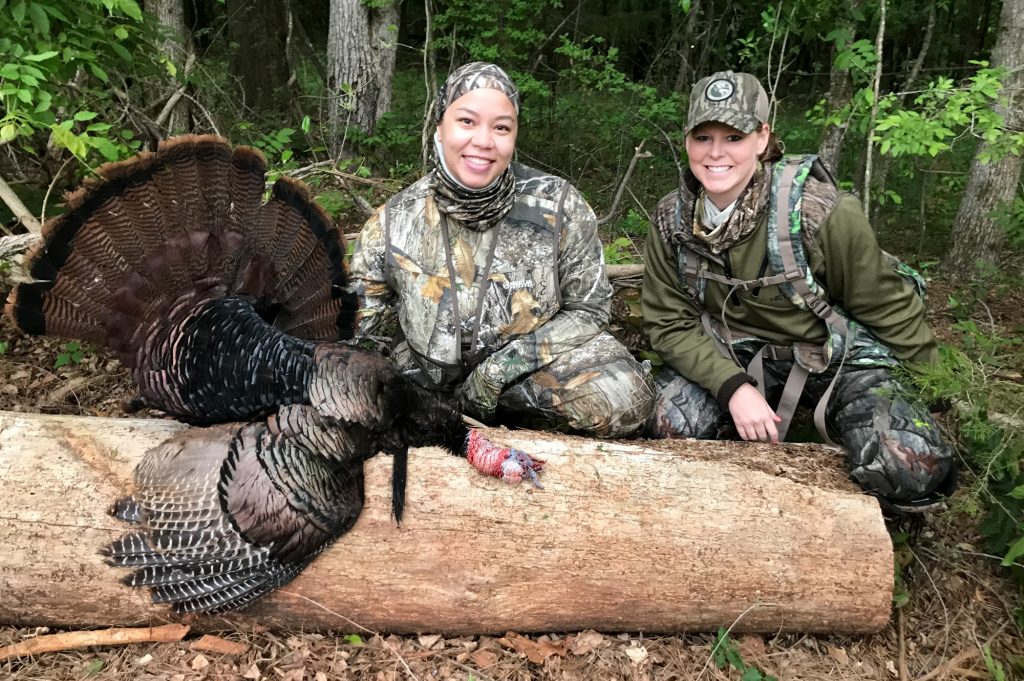 two female hunters pose with a harvested turkey