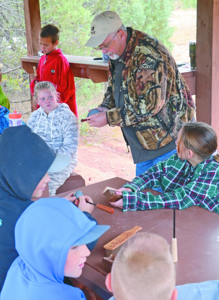 adult using turkey call in table full of kids