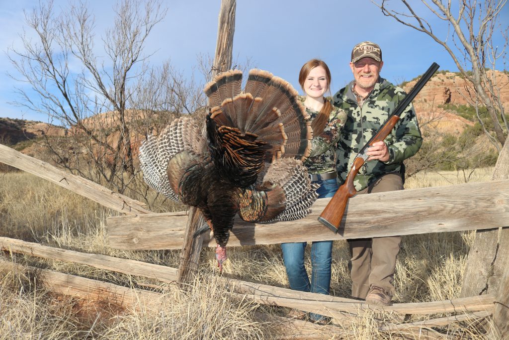 Father and daughter pose with harvested wild turkey.