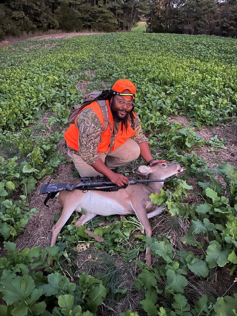 A hunter poses with their recently harvested deer.