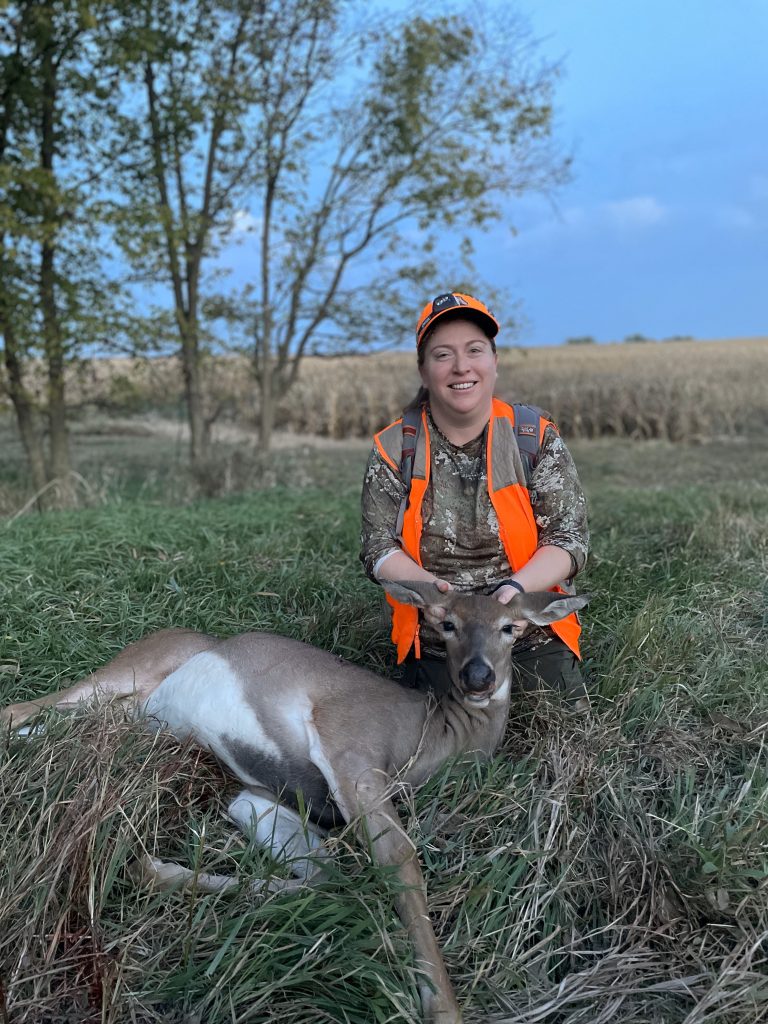 A hunter poses with their recently harvested deer.