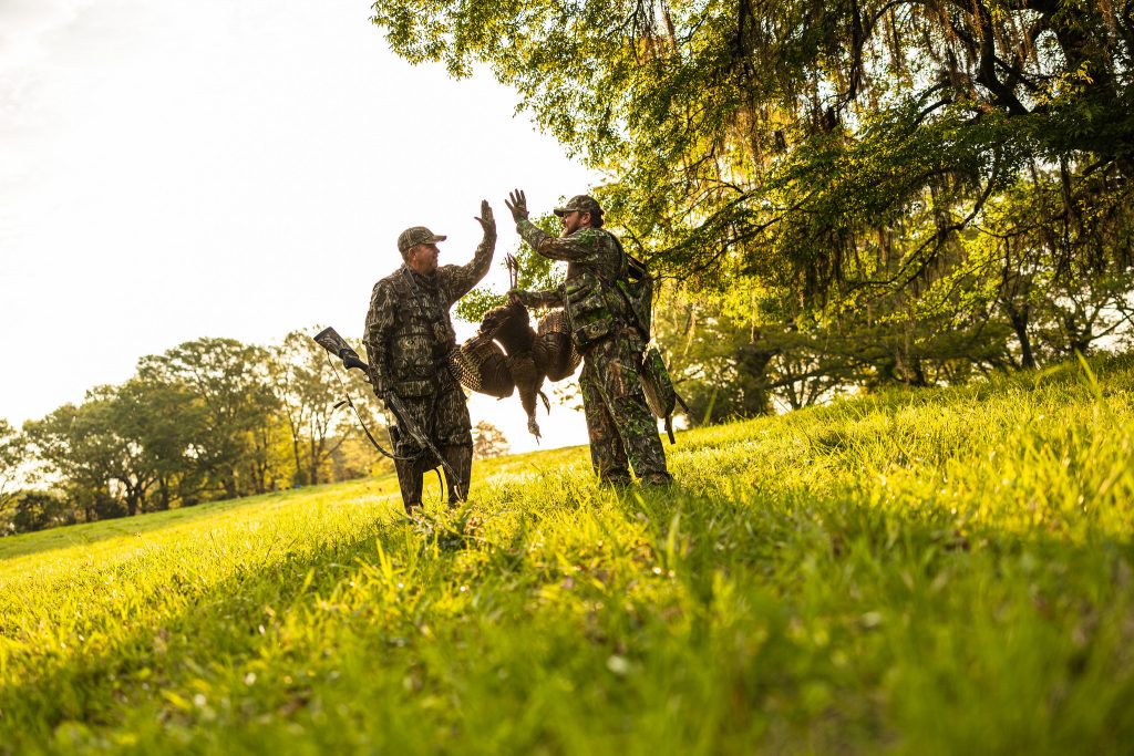 two hunters with a turkey high fiving