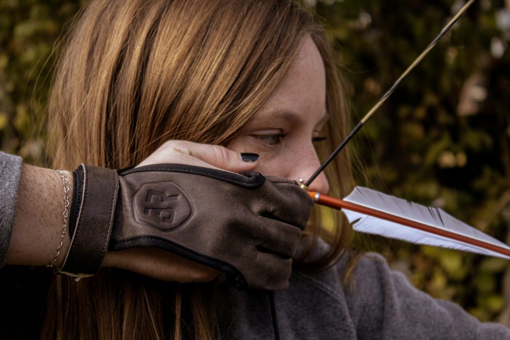 A hunter uses her recurve bow with her archery glove.