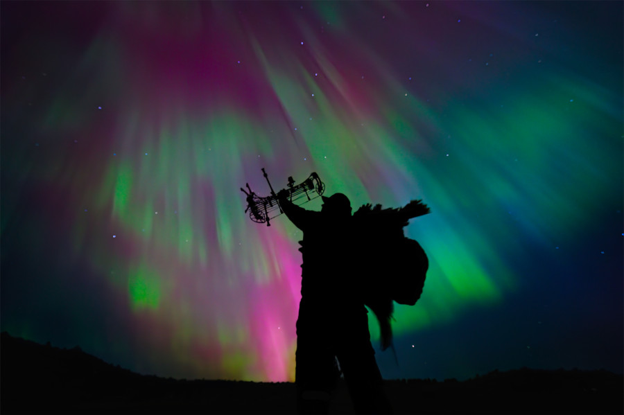 A hunter celebrates his harvest with the northern lights in the background. 