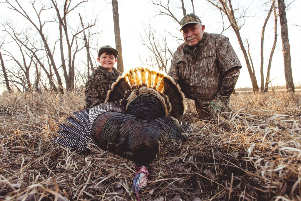 Tommy Glines with his grandson and a harvested wild turkey.