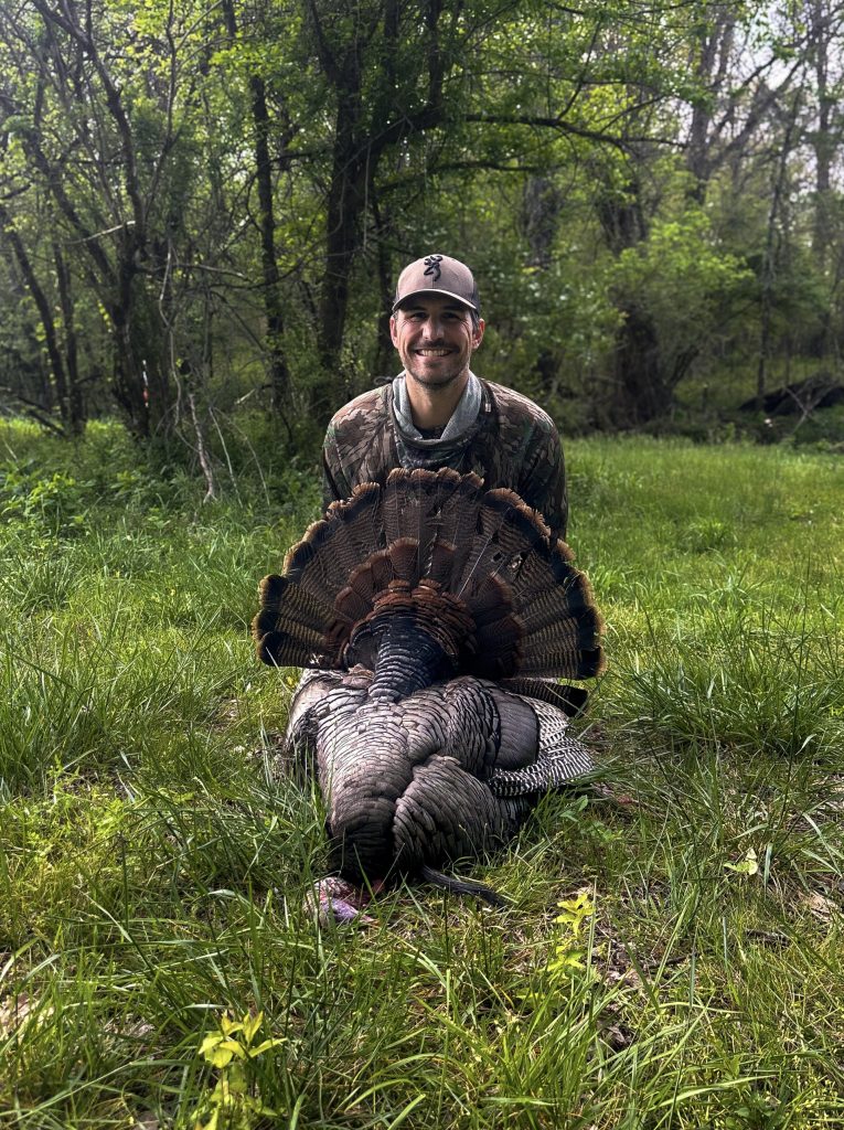 A hunter with a harvested wild turkey.