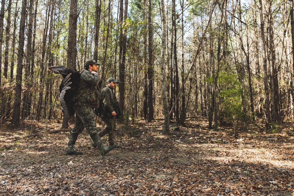 Hunters walk out of a forest after a hunt.
