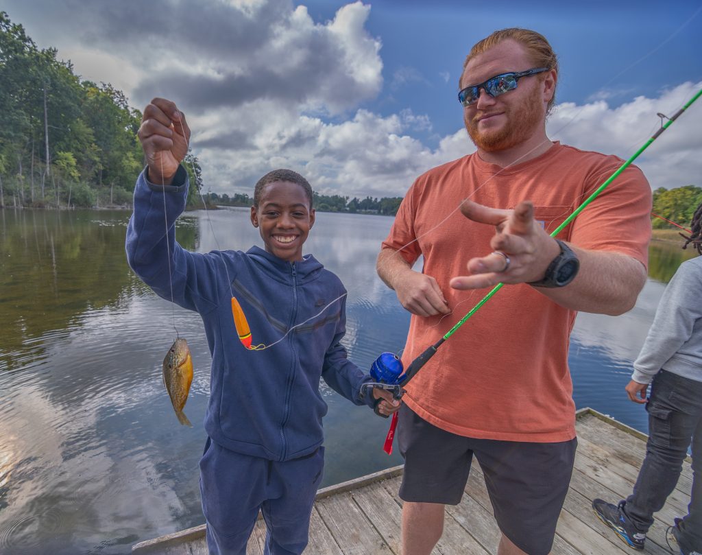 A youth and mentor reel in a fish